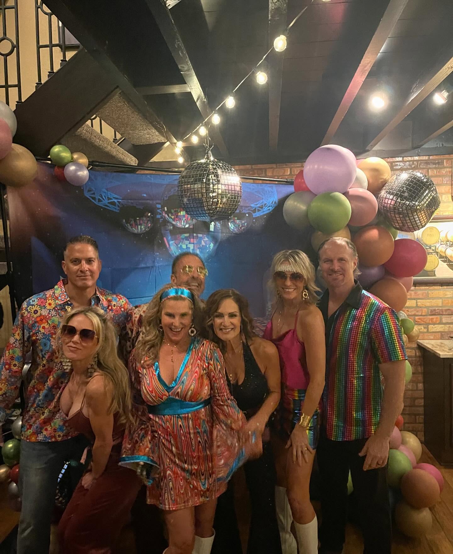 Retro themed event guests posing at a disco backdrop